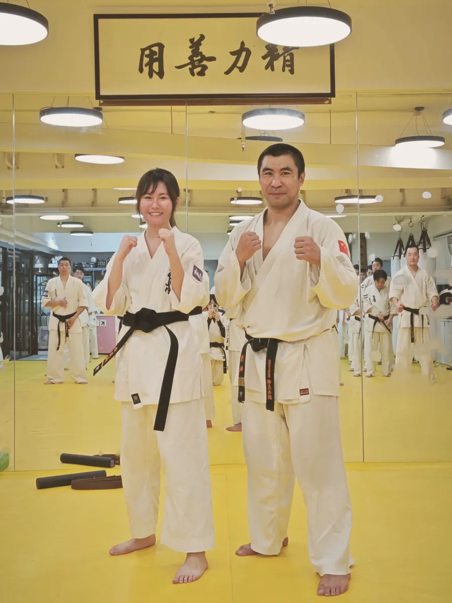 Claire in a white uniform and black belt beside her instructor